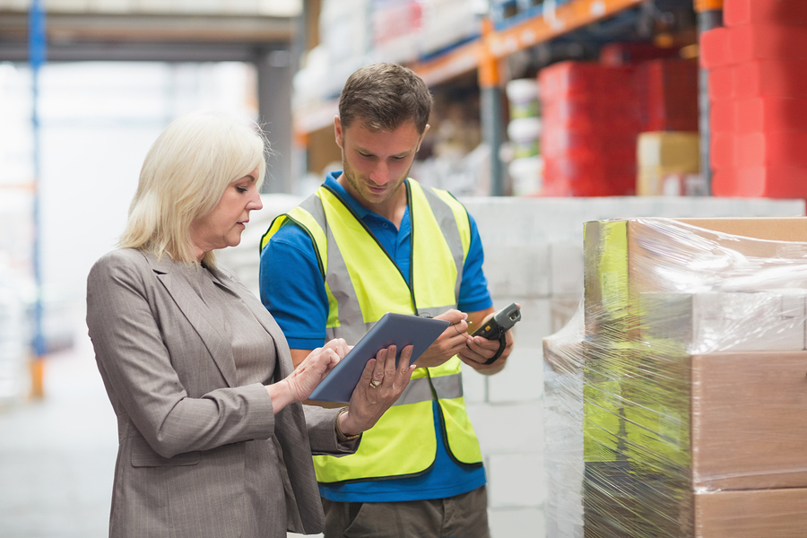 Manager using Workflow solution on tablet while worker scanning package in warehouse