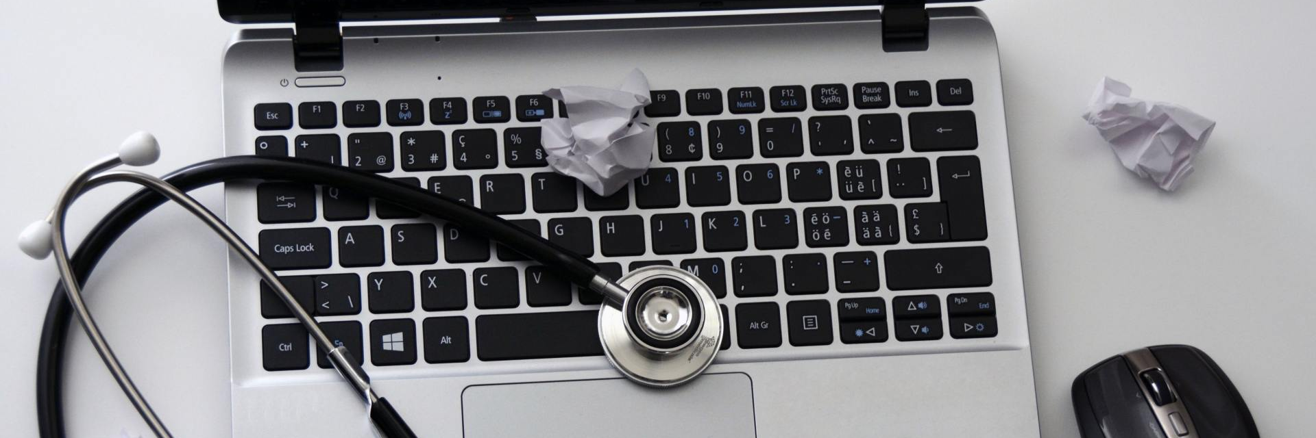 Laptop with stethoscope and crumpled paper on it.